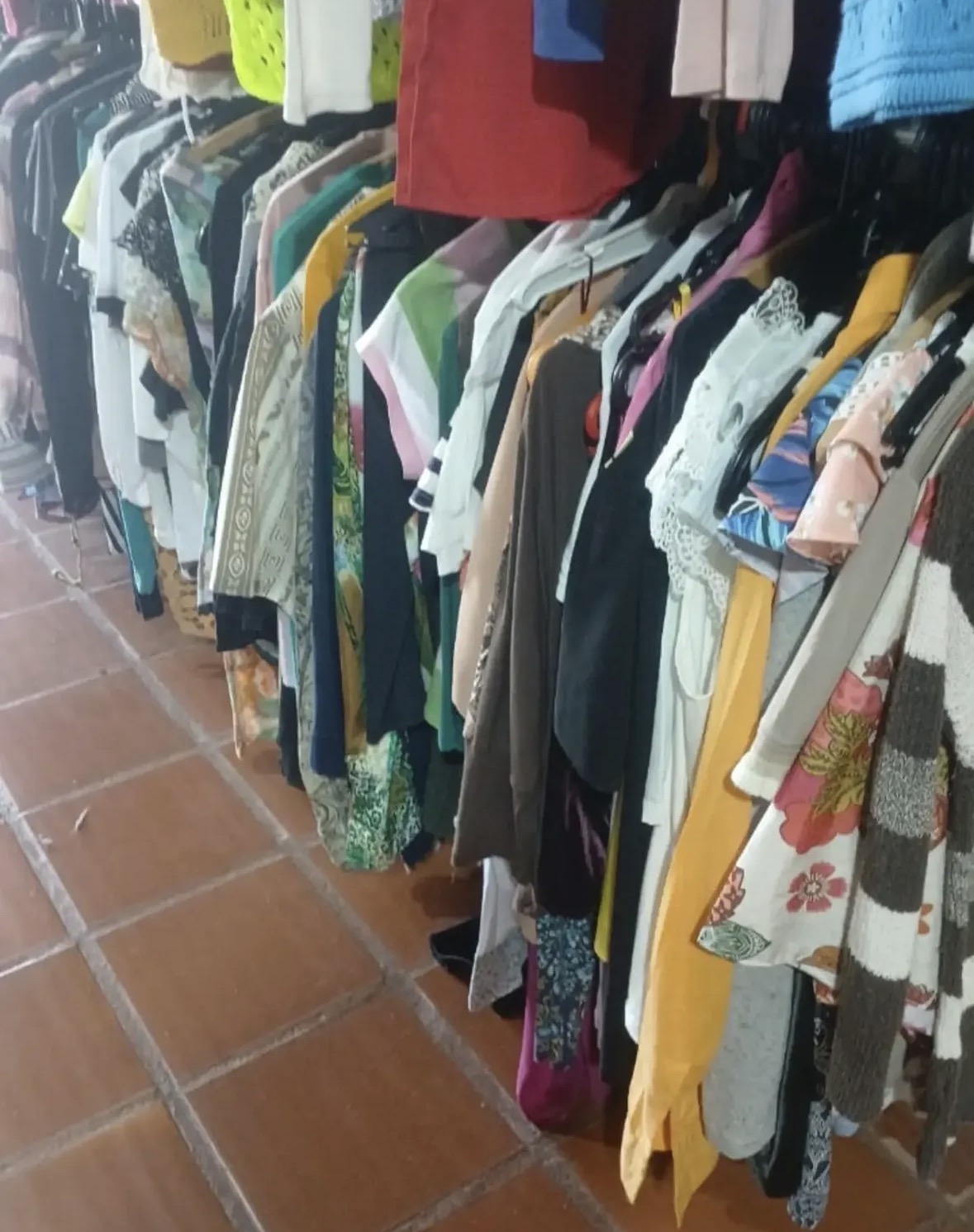 Fileira de roupas coloridas penduradas no Bazar Beneficente da APRAPI